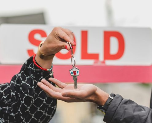 Hand placing house key in another person's hand